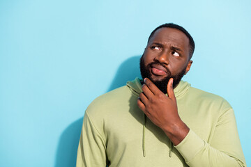 Portrait of minded pensive man arm on chin look interested empty space isolated on blue color...