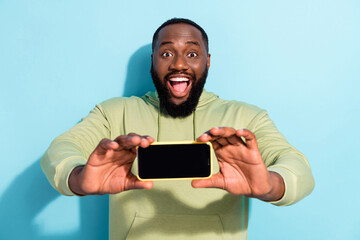 Photo of astonished positive man demonstrate empty space telephone screen proposition isolated on...