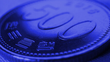Translation: Bank of Korea. 500 won coin close-up. Dark blue tinted background or wallpaper on an economic, financial or banking theme. Money and business in South Korea. Korean won. Macro