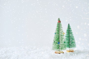 Small Christmas trees on a light background. Toy green trees in a snowdrift. 