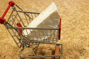 camembert cheese in shopping cart on grunge background