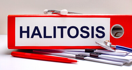 On the desktop is a stethoscope, documents, a pen, and a red file folder with the text HALITOSIS. Medical concept