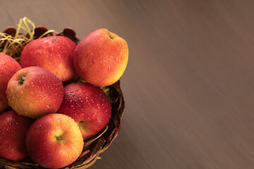 A vase of red apples on a uniform brown background. Wicker basket with seasonal harvest fruits