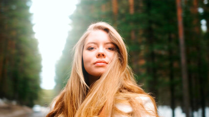 Obraz premium Beautiful woman with a magnificent golden hair. Fun happy young girl shake her head to make hair flying. Attractive young lady turns around and looks into the camera
