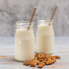 Almond milk in bottles with almonds. Almond milk on a light background.