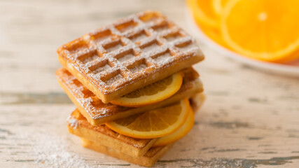 Delicious waffles with orange slices on a light background