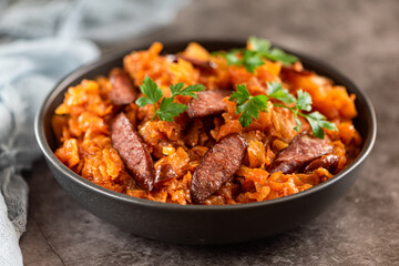 Stewed cabbage with sausages in black plate. horizontal view from