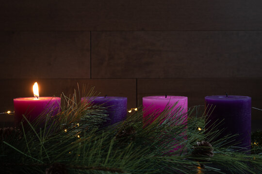 Single candle lit on advent wreath for first week of advent with pillar candles, wood background and copy space