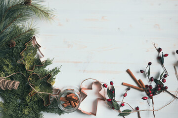 Border with Christmas presents, evergreens, red berries and copper cookie cutters on white with...
