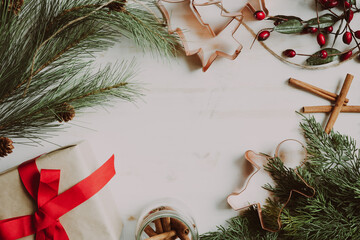 Christmas frame with presents, evergreens, red berries and copper cookie cutters on white with copy space
