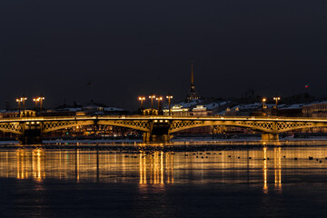 Fototapeta na wymiar The panoramic footage of the winter night city Saint-Petersburg with picturesque reflection on water, Isaac cathedral on background, Blagoveshchensky bridge, old name is the lieutenant Schmidt