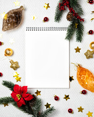 Christmas background with notebook paper, fir tree branches, poinsettia, and festive decor. Flat lay and top view. Christmas and New Year resolutions concept.