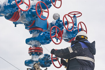 A gas company worker opens and closes high pressure valves on a gas tree