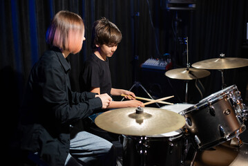 Young woman teaching boy to play drums.