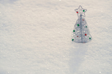 The Christmas background with small decorative Christmas tree in the white, fluffy snow. Greeting card image with space for copy.