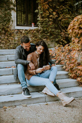Fototapeta na wymiar Young couple sitting on outdoor stairs on a autumn day