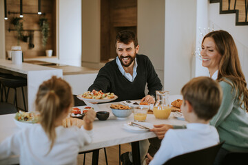 Young happy family talking while having breakfast at dining table