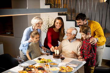 Family celebrating grandfather birthday with cake and candles at home