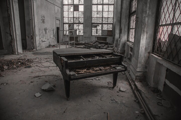 An old abandoned grand piano in an old abandoned building. An ancient musical instrument. The interiors of an abandoned Soviet building. Shabby walls.