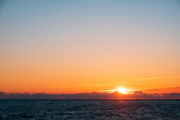 sunset on the sea, the horizon line of the sun and small clouds. orange sky during sunset