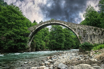 Ancient stone arch bridge and mountain river	