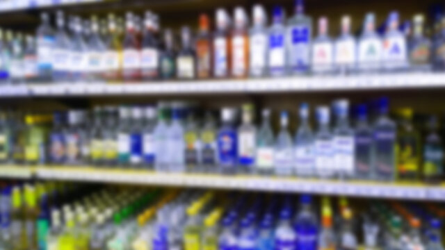 Abstract blur image of supermarket background. Defocused shelves with bottles of alcohol, vodka, cognac, brandy, wine, beer. Retail industry. Price. Concept of alcohol sale regulation. Ban. Inflation.