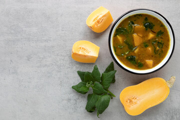 Soup from butternut squash and spinach leaves in enamel bowl. Top view comfort food with copy space;