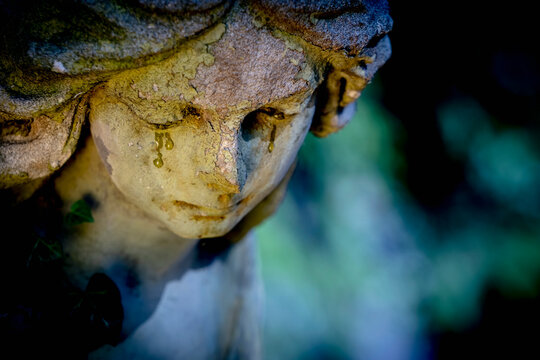 Sad ngel with tears in the eyes. Fragment of an antique statue. Death concept. Copy space.
