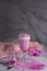 Pink matcha latte in a glass on a gray background. A trendy drink with dragon fruit powder. Super food, detox, diet. Vertical photo.
