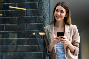 Portrait of successful woman with mobile in urban background. Business technology device concept