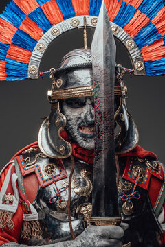 Dead roman soldier with bloody sword against gray background