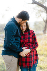 Man hugs a pregnant woman while holding his hand on her belly