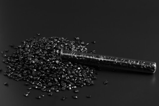 Many black granules of polypropylene, polyamide in a test tube. Background. Plastic and polymer industry, industry. Microplastic products.