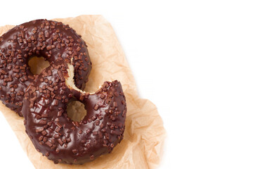 Isolated two chocolate bitten donuts on a white background. Sweet fast food concept. Top view, flat lay, copy space.