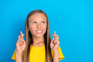Obraz premium Photo of nervous little lady crossed fingers look empty space wear yellow t-shirt isolated blue color background