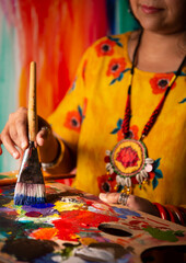 Woman's hand with bangles holding a painting palette 