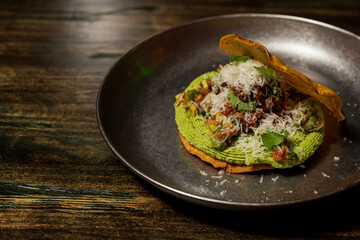 Corn cake or taco stuffed with avocado and different organic vegetables with a lime and cinnamon dressing and cheese sprinkled on top