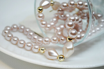 Wedding decor: a string of pink pearls in a glass on a white plate