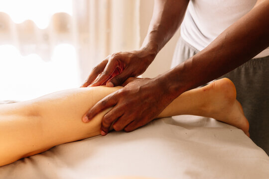 Hands of african american professional therapist giving a leg massage