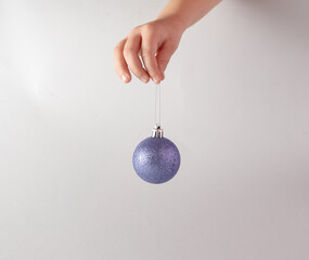 Hand holding Christmas bauble decoration. Minimal New Year concept art