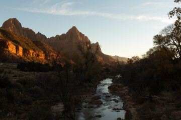 Low winter afternoon sunlight paints glowing orange light on the Watchman mountain and the nearby...