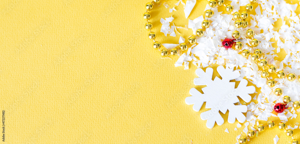 Poster white snowflake and beads with artificial snow on a yellow background, empty space for text, festive
