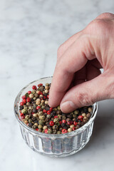 Hand grabbing pepper seeds from a bowl