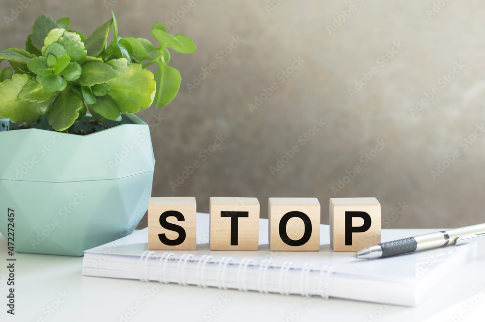 Poster four wooden cubes arranged in stack with word stop on them on the office table