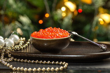 Red caviar in a ceramic bowl, silver beads and pearls on a silver tray. Christmas and New Year background