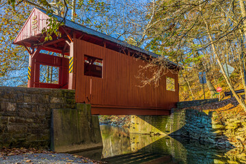 A bright red covered bridge over a stream in the middle of Mingo Creek County Park.