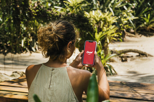 Girl in the park holding a smartphone with Ifood app on the screen. Online food ordering and food delivery platform. Rio de Janeiro, RJ, Brazil. November 2021