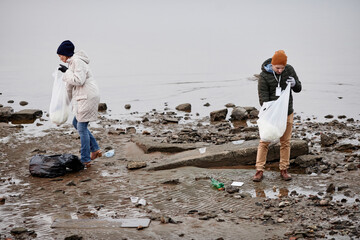 High angle view at volunteers picking up trash at sea shore, ecology and environment concept, copy...