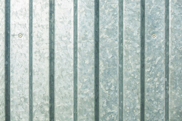 The wall is made of gray profiled metal sheet. A galvanized zinc pattern is visible on the surface. Background. Texture.