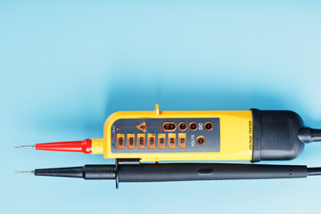 Yellow tester for step-by-step indication of voltage in an electrical circuit on a blue background.